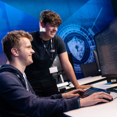Two people working on a cyber course, with computer in front of them